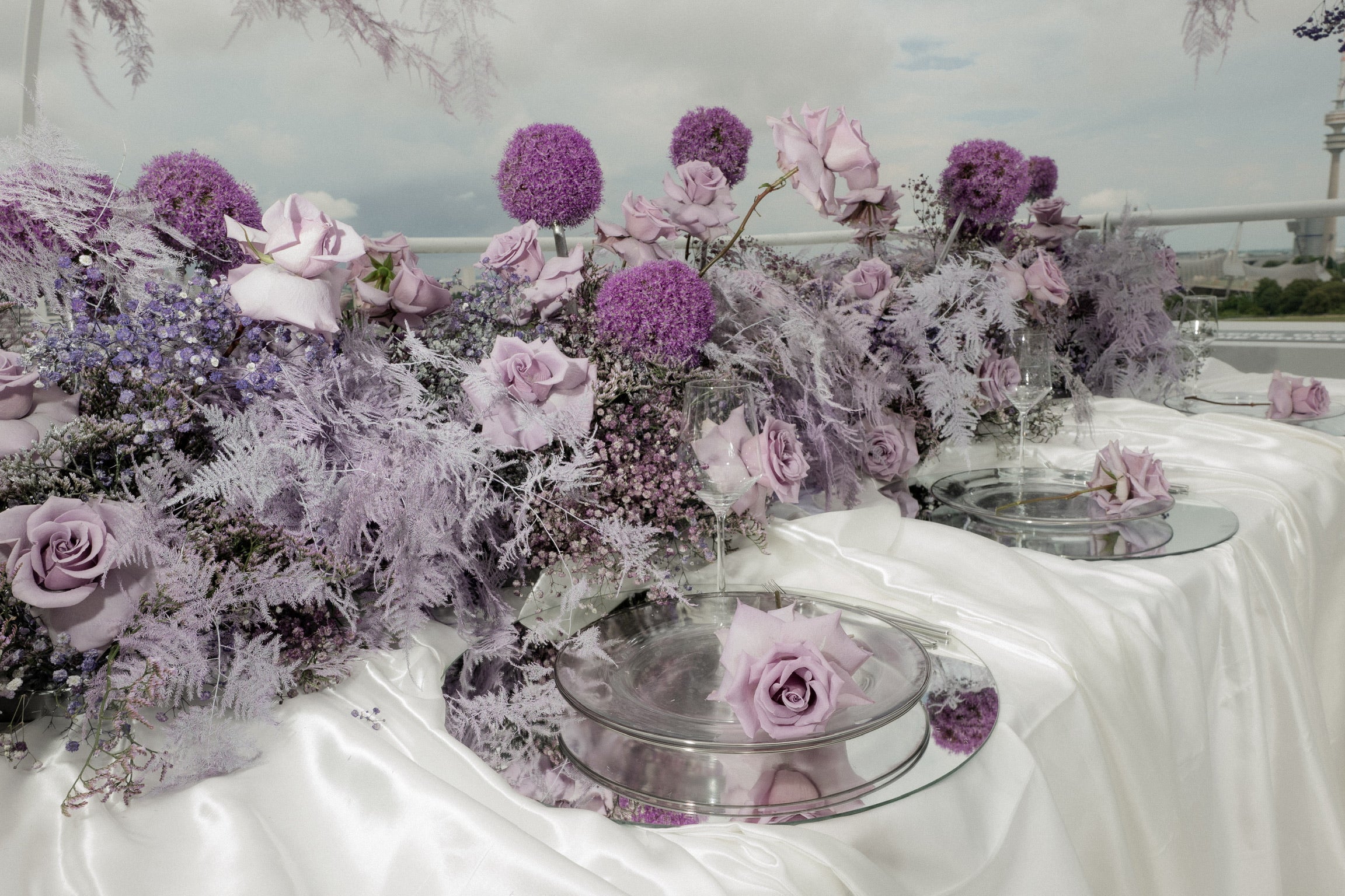 Tisch mit weisser Tischdecke und Hochzeitsblumen von ZANOZA in lila für aussergewöhnliche und extravagante Hochzeiten