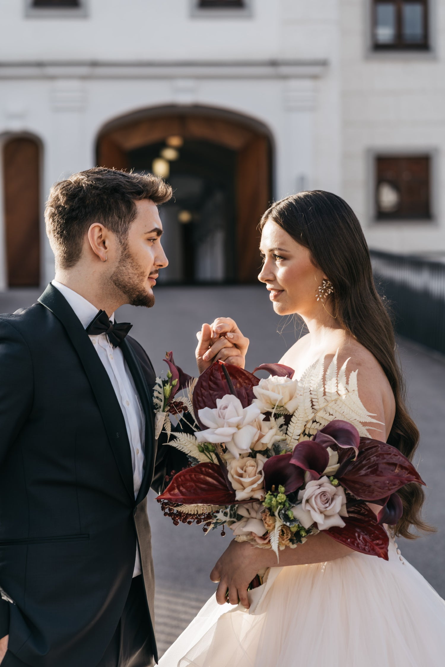 Brautpaar mit Blumenstrauß von Zanoza mit weinroten Calla und Anthurien, beigen XXL-Rosen und Beeren für High-End-Hochzeiten
