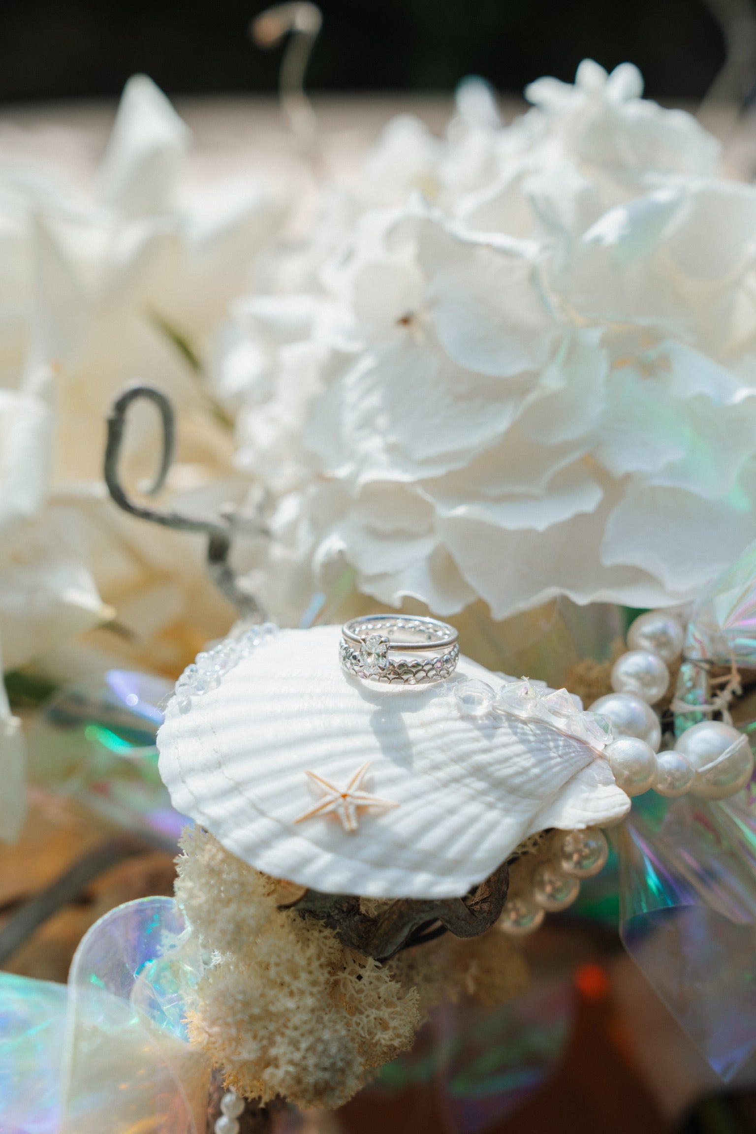 Ringe auf Muschel mit Perlen im Hintergrund